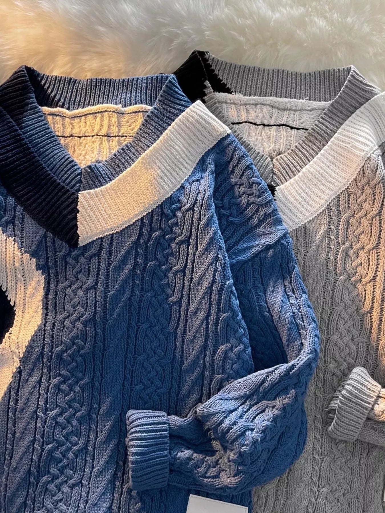 Two URBAN UNIT Fracture Knit Sweaters in Deep Water Blue and Concrete Grey laid flat. High-contrast asymmetrical streetwear design. Built for discipline and freedom.