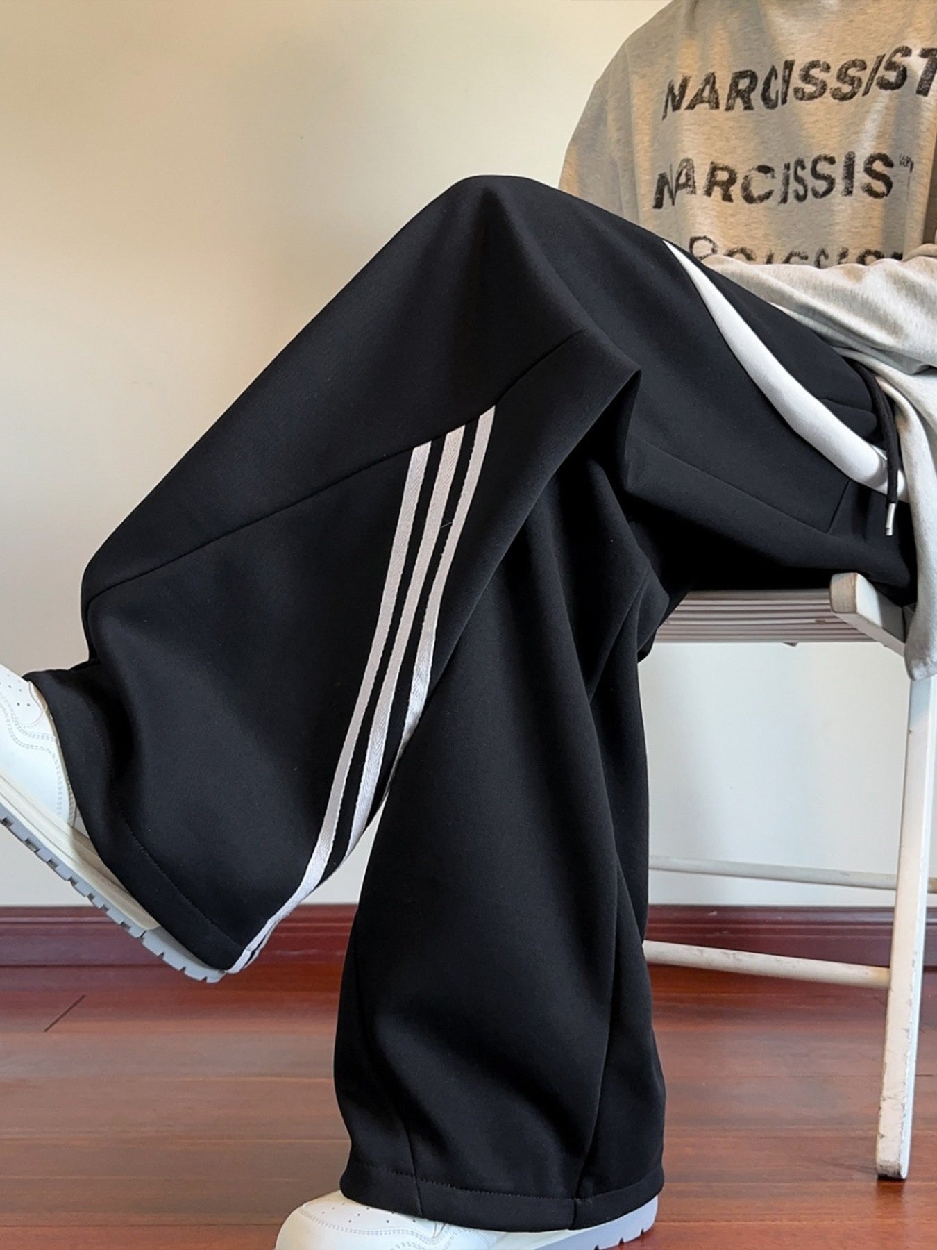 Model sitting in the black Arc Silhouette sweatpants, demonstrating the "Plus Size Optimized" comfort and fabric flow of the wide-leg cut.