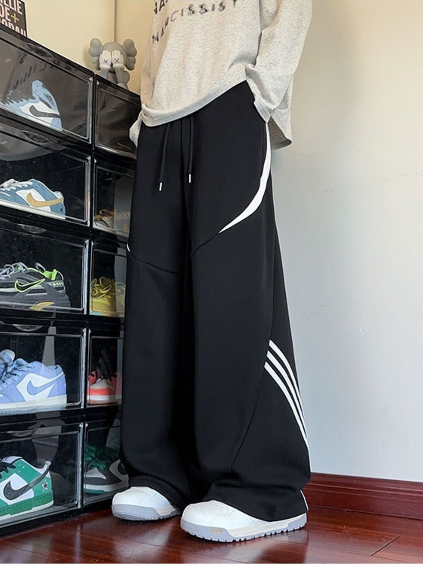 Urban lifestyle shot of the black Arc Silhouette pants paired with sneakers, showcasing the industrial aesthetic and bottom stripe detail.