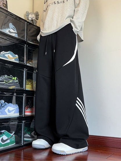 Urban lifestyle shot of the black Arc Silhouette pants paired with sneakers, showcasing the industrial aesthetic and bottom stripe detail.