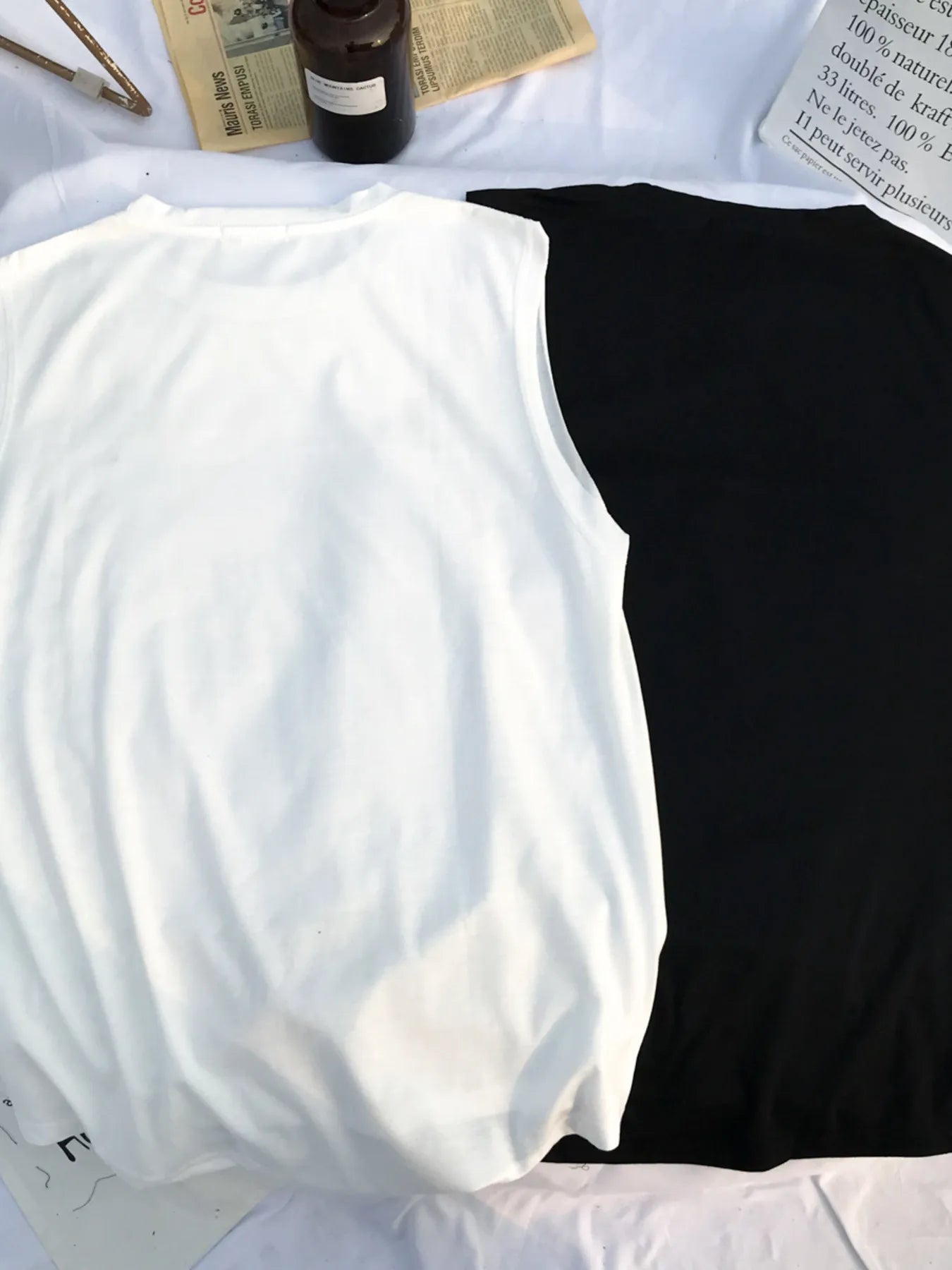 URBAN UNIT Morning News Graphic Tank showing the Raw White and Midnight Black colorways. Back view of the loose-fit sleeveless streetwear design.