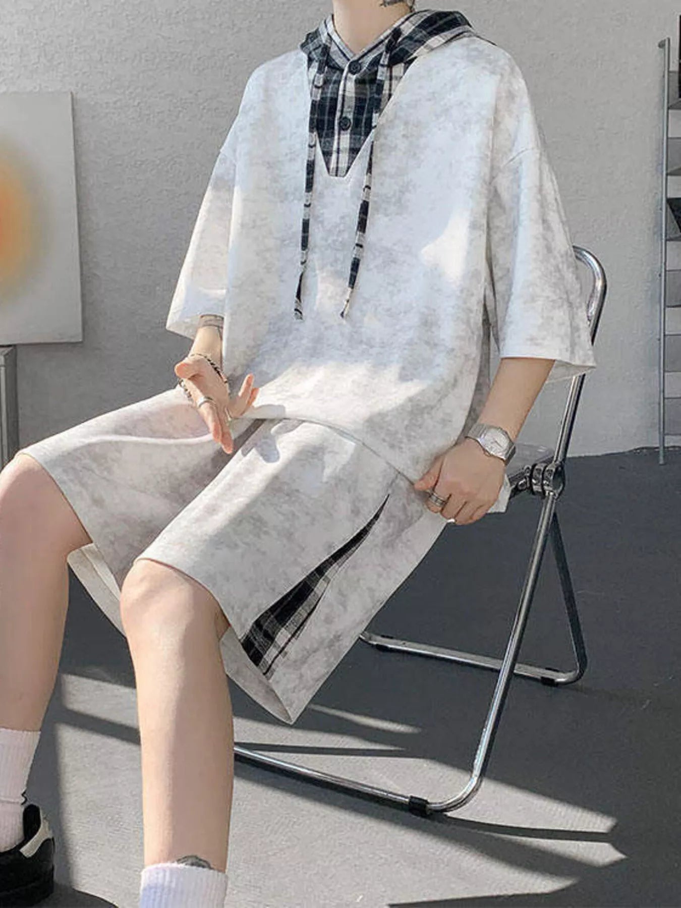 Model sitting wearing the URBAN UNIT VANGUARD Layered Set in Concrete Ash, showcasing the comfortable, plus-size optimized leg room and side plaid panels on the shorts.