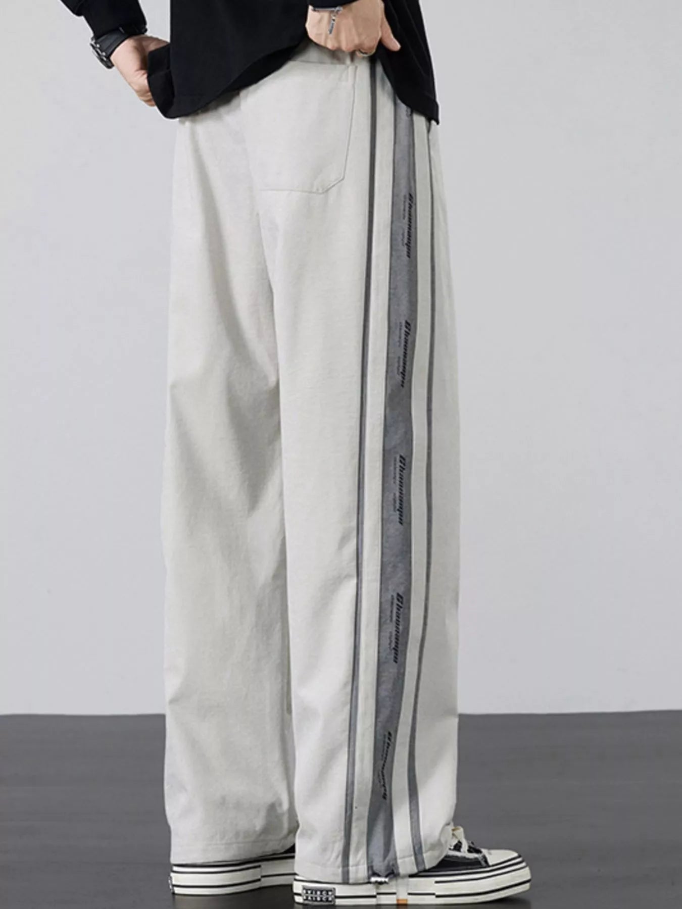 Side profile of the Industrial Beige wide-leg cargo pants on a model, highlighting the signature triple-stripe branding.