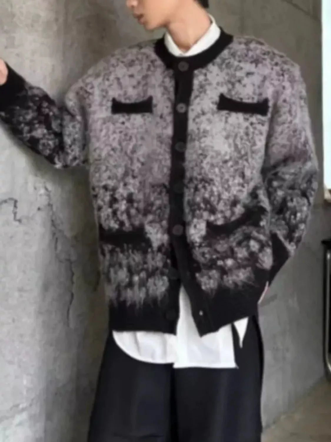 Close-up of the URBAN UNIT Static Gradient Cardigan against a raw concrete wall. Highlighting the heavy-knit texture, sleeve drape, and industrial street aesthetic.